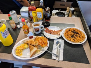 allysoneatz at waffle house taking a photo of eggs, toast, chocolate chip waffle and hashbrowns and bacon